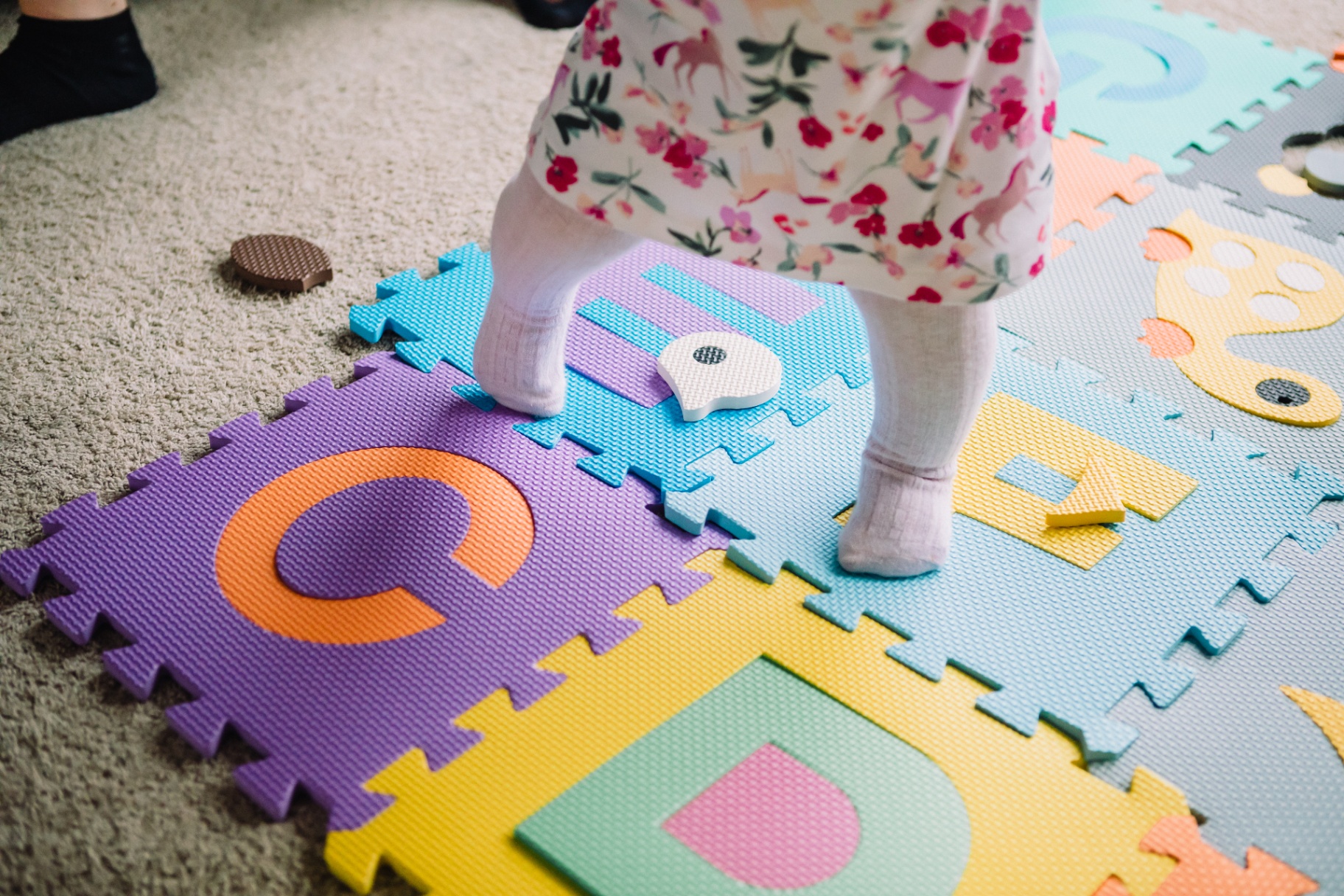 Toddler standing on the colourful alphabet foam puzzle mat
